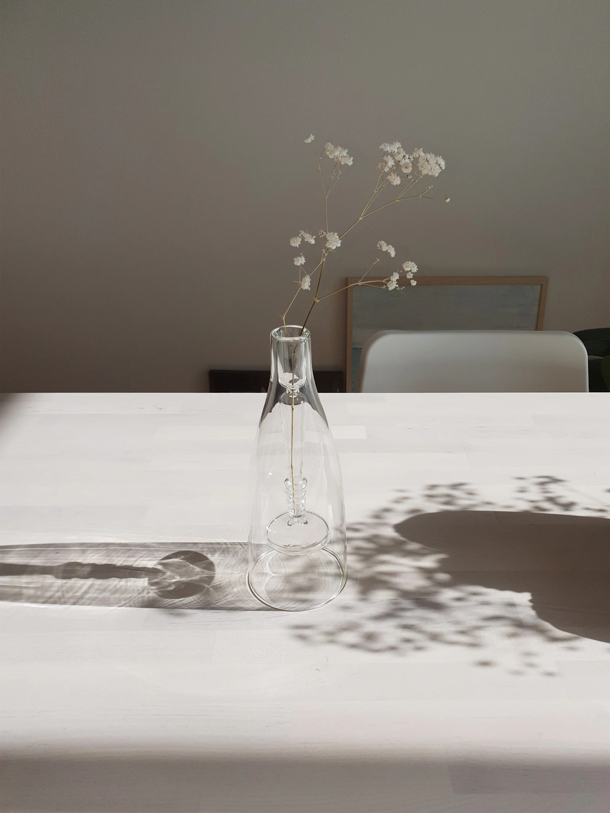 Florero de vidrio transparente con ramas en un ambiente luminoso